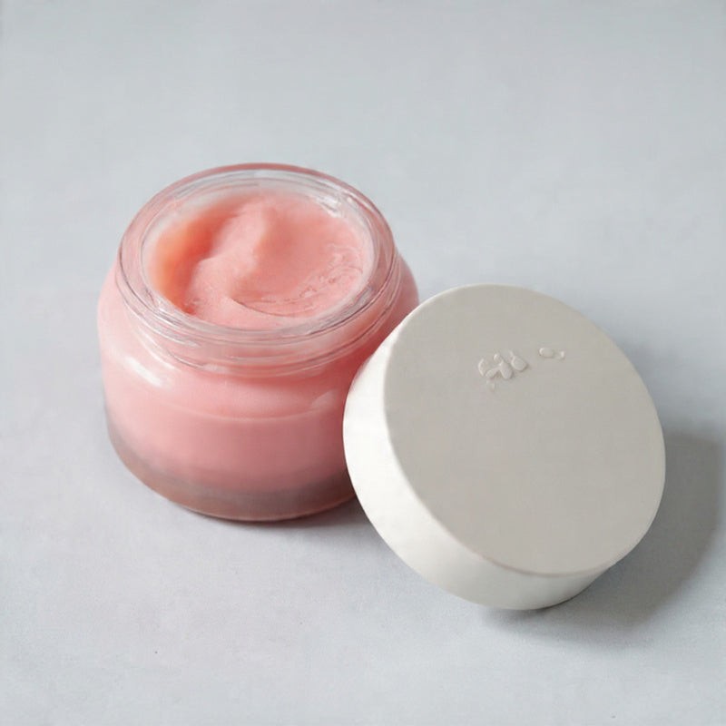 Pink lip balm jar with a white lid on a light gray background