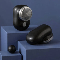 Black electric shaver on a blue geometric platform with a dark blue background