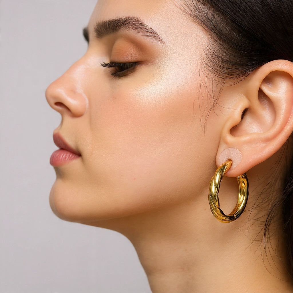 Close-up of a woman wearing a gold hoop earring against a neutral background